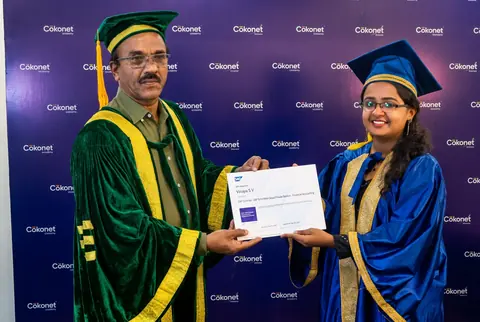 A Cokonet graduate in a blue convocation robe receiving her certificate on stage