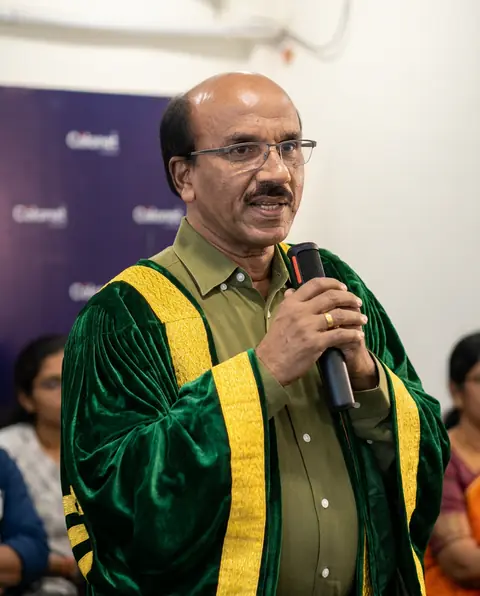 A speaker in a green convocation robe addressing the graduates