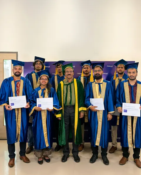 Cokonet graduates in blue convocation robes holding their certificates